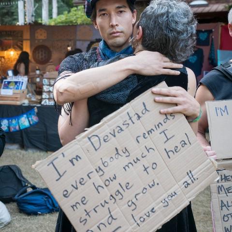 Two people hugging holding Vulnerability signs.