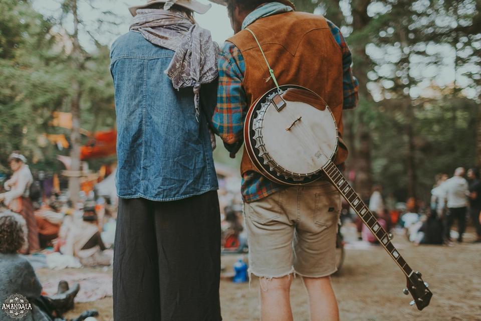 two people stand side by side, one with a banjo slung over their back two people stand side by side, one with a banjo slung over their back