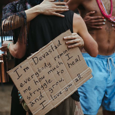 two people hugging, one holding a cardboard Vulnerable Rally sign