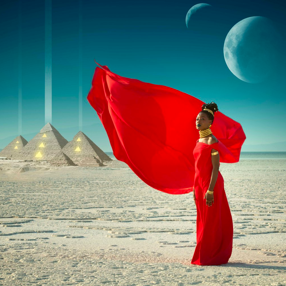 Fatoumata in a red dress in the desert with pyramids