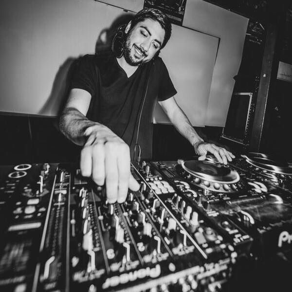 Blake Rudolph in black and white twiddling knobs as DJ