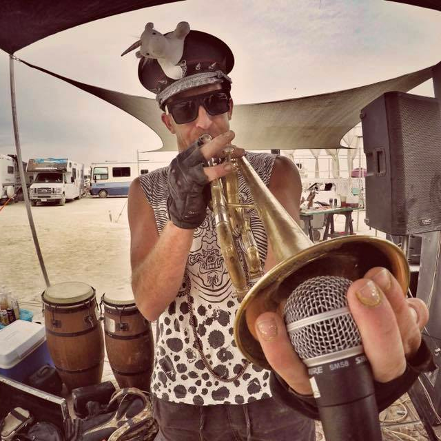 Paul holding a horn into a mic in the desert