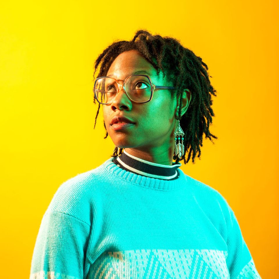 Amenta in blue sweater on a yellow background