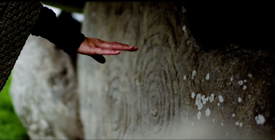 Peia's hand touching ancient stone
